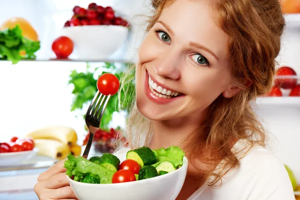 Woman eats healthy food vegetable vegetarian salad about refrige