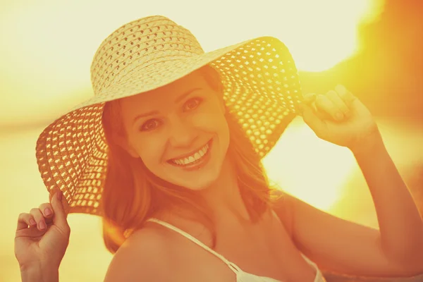 Beauty happy smiling woman in hat at sea at sunset on beach