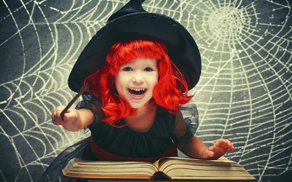 Halloween. cheerful little witch with magic wand and book conjur