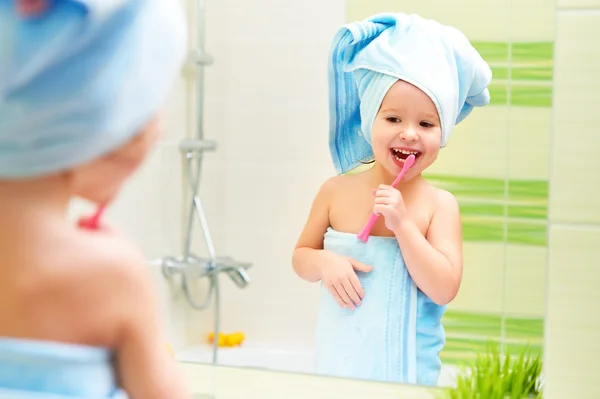 Funny little girl cleans teeth with toothbrush in bathroom