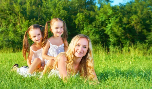 Happy family mother and children twin sisters on meadow in summe