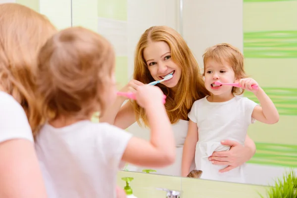Happy family mother and daughter child brushing her teeth toothb