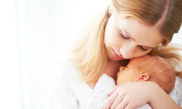 Newborn baby in tender embrace of mother