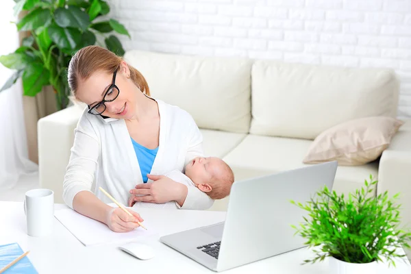 Business  mother works at home via Internet with newborn baby