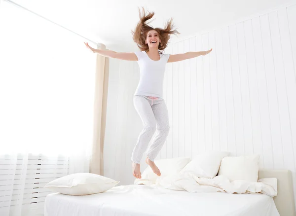 Happy girl jumping and having fun in bed