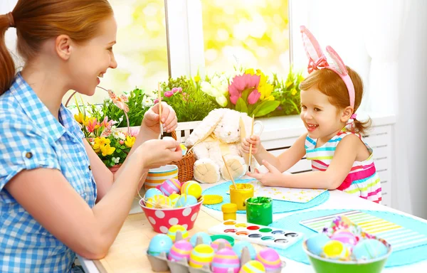 Happy family mother and child girl paints eggs for Easter