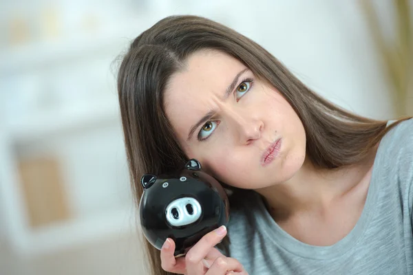 Woman guessing how much money is in her piggy bank
