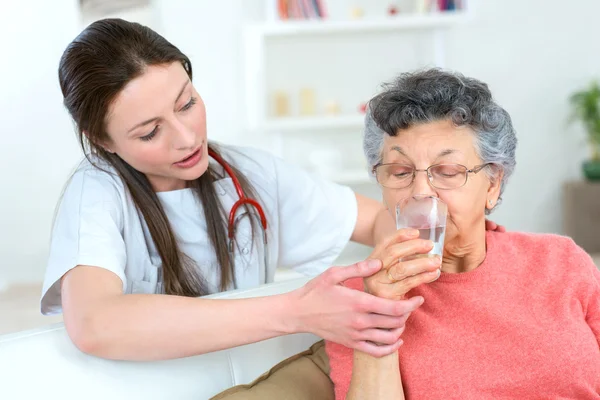 Giving senior woman a drink of water