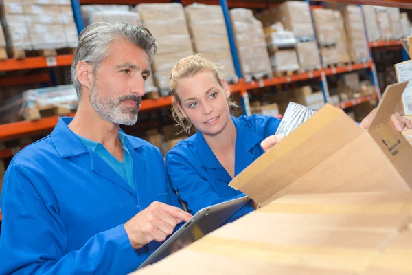 Man and woman opening box in warehouse