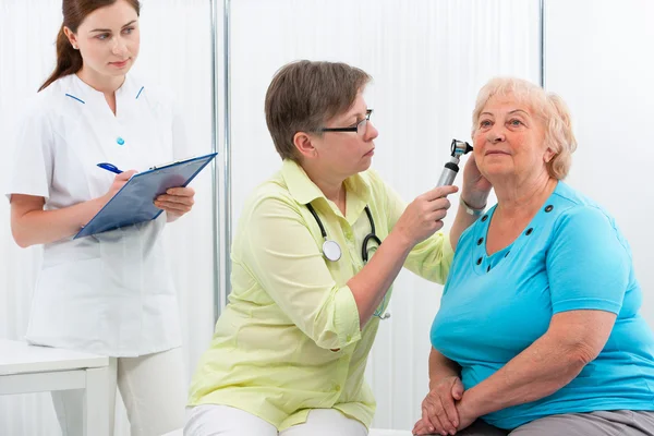 ENT physician looking into patient\'s ear with an instrument