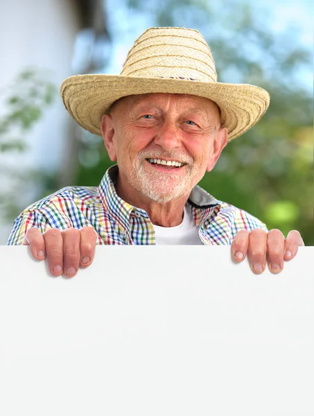 Senior man with a straw hat holds a blank board
