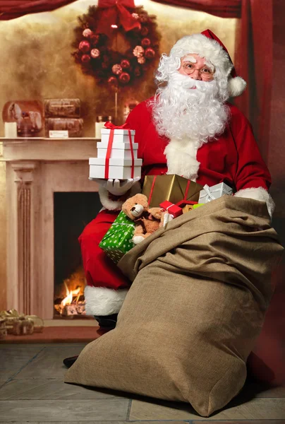 Santa Claus with a bag of presents at the fireplace