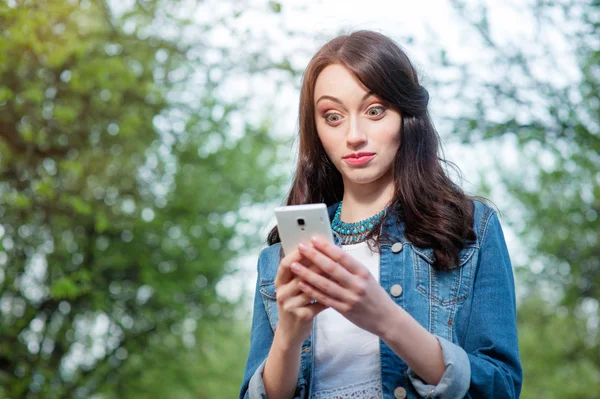 Amazed young woman using smartphone