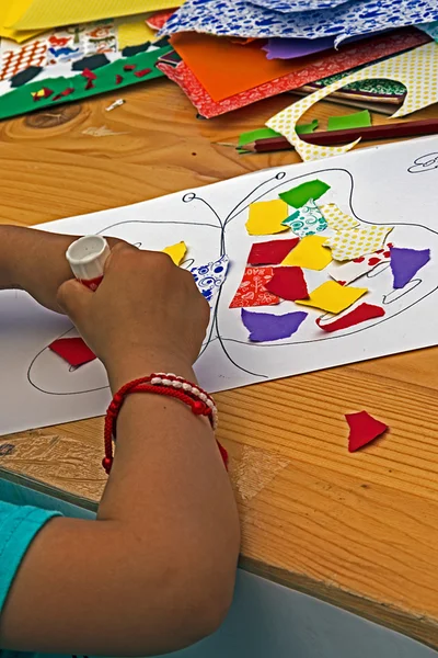 Child which sticks together pieces of colored paper