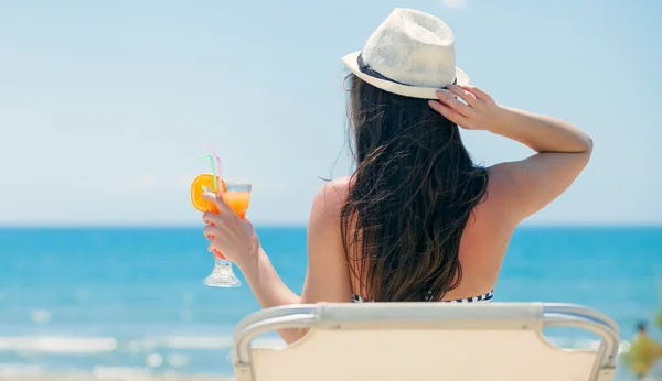 Woman with cocktail on the beach during tropical vacation