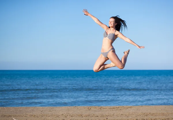 Woman jumping on the beach enjoying summer vacation