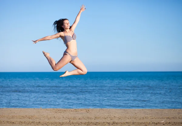 Woman jumping on the beach enjoying summer vacation