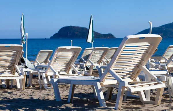 Empty lounge chairs on sandy beach before summer season