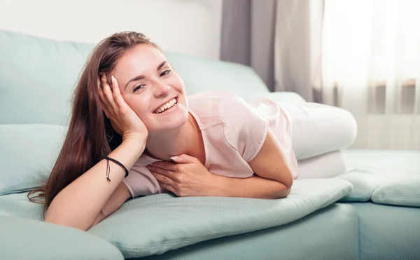 Happy young woman lying on couch and relaxing at home. Casual style indoor shoot