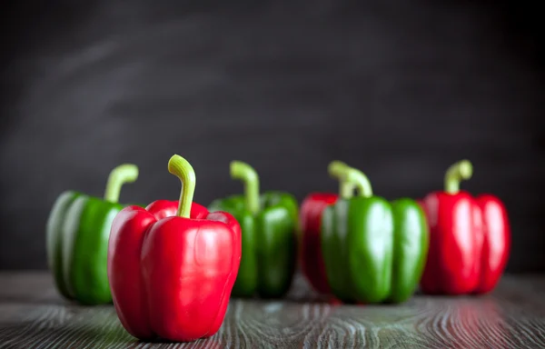 Red and green bell pepper on wooden board dark background copy space