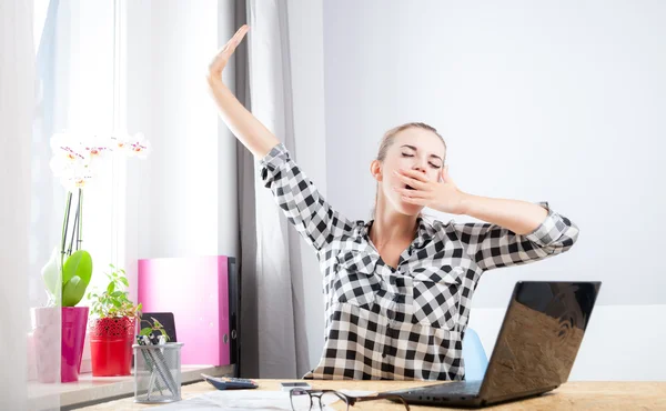 Tired woman yawning during working in home office using laptop