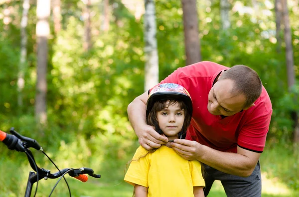 Father dresses his daughter's bicycle helmet