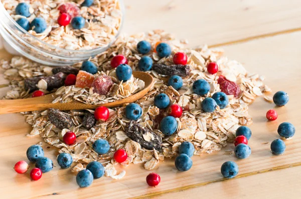 Serving muesli with scattering of wild berries on wooden table