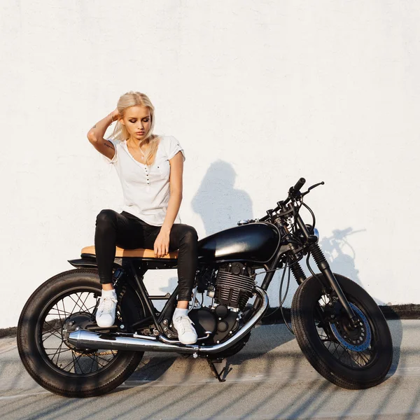 Biker girl sitting on vintage custom motorcycle