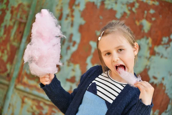 Adorable little girl eating candy-floss outdoors at summer