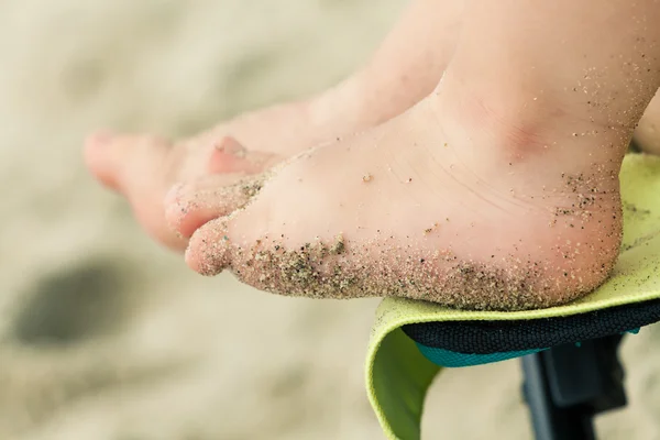Close up of toddler\'s feet covered with beach sand. Photo with u