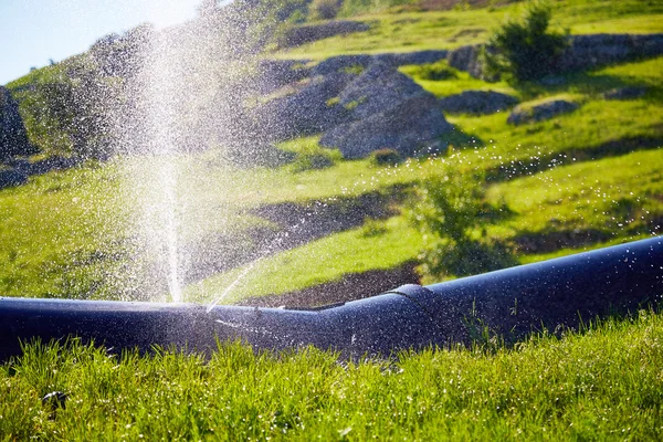 Water splashes under pressure from the damaged pipe.