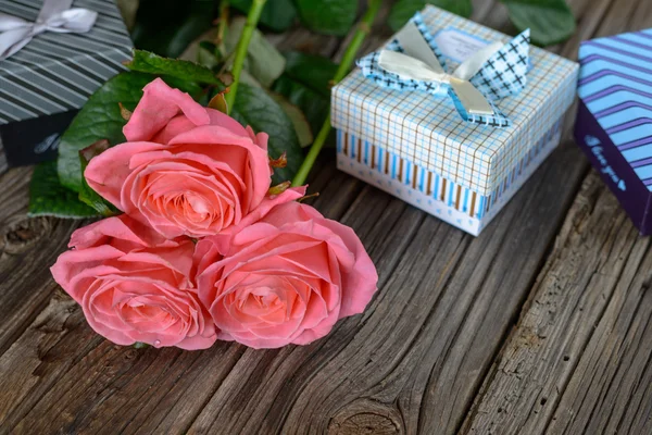 Bundle of roses and gifts on table