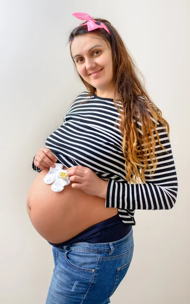 Pregnant woman holding tiny baby booties