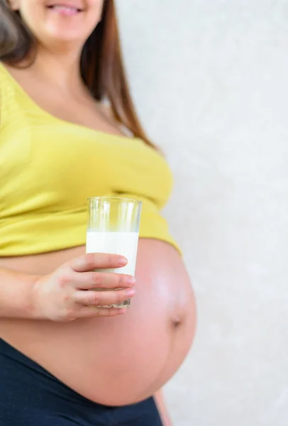 Smiling pregnant woman with a glass of milk