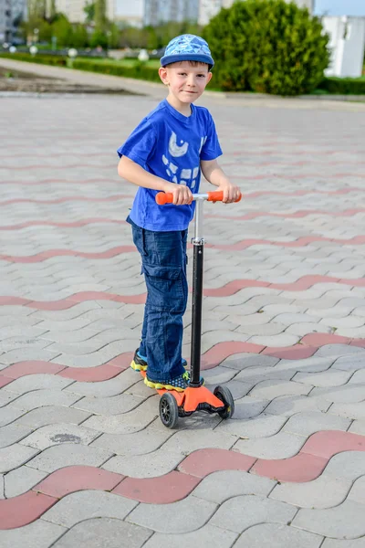 Handsome young boy standing on a toy scooter