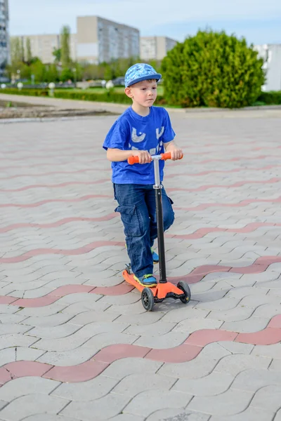 Handsome young boy standing on a toy scooter