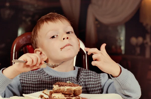 Contented little boy eating cake for dessert