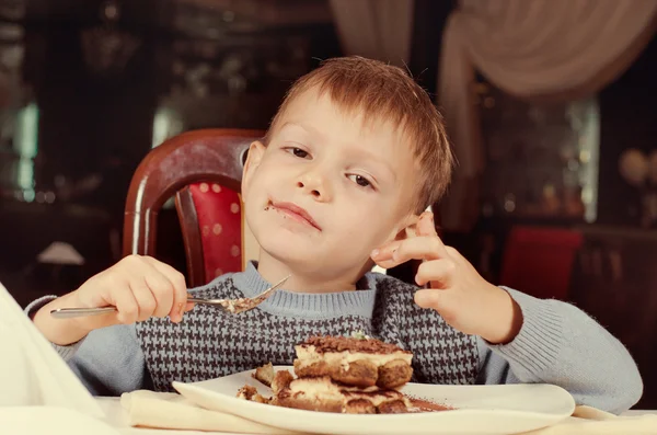 Contented little boy eating cake for dessert