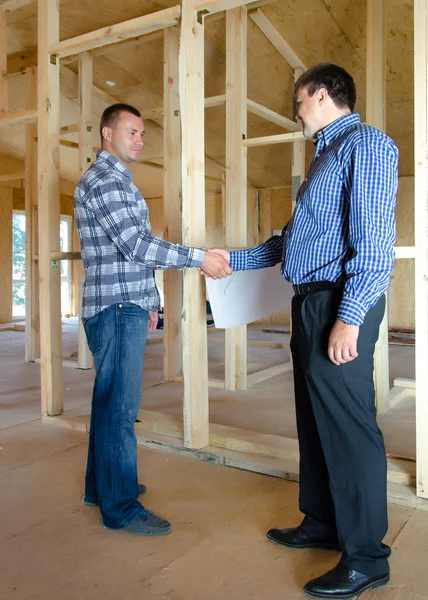 Two men shaking hands in a new build house