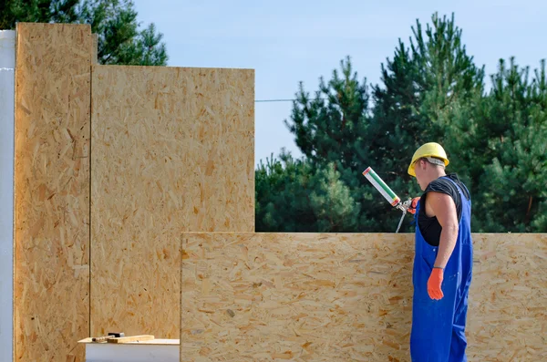 Builder applying glue to a wooden wall panel