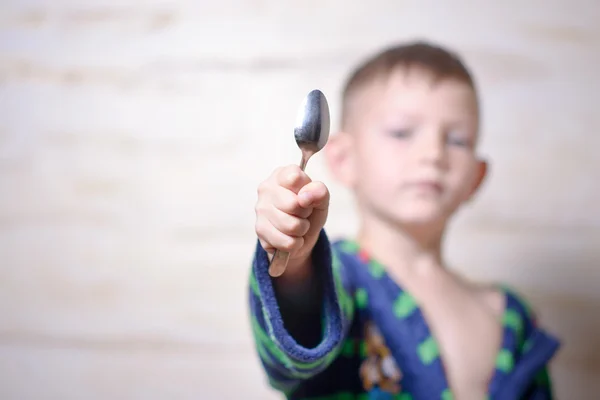 Young boy holding out a kitchen spoon