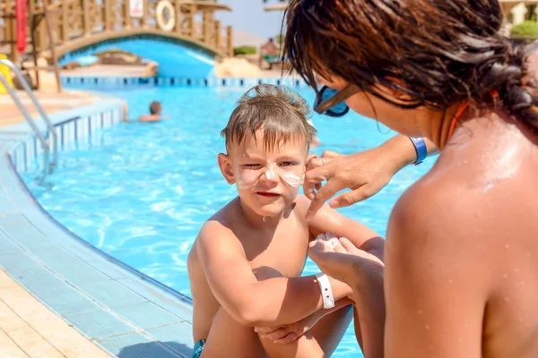 Mother putting sunscreen on her sons face