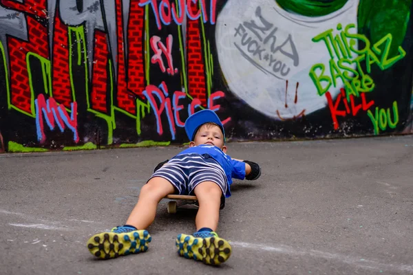 Young boy lying on his skateboard