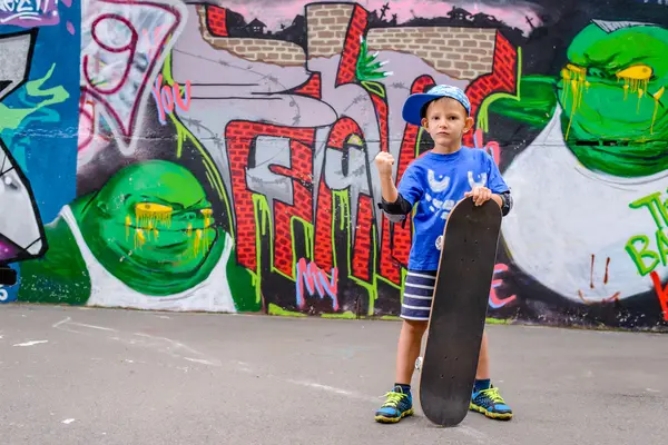 Young skateboarder posing with his board