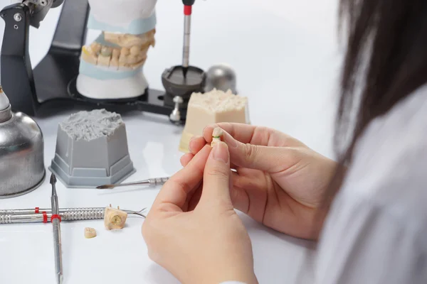 Dental technician working with articulator in dental laboratory