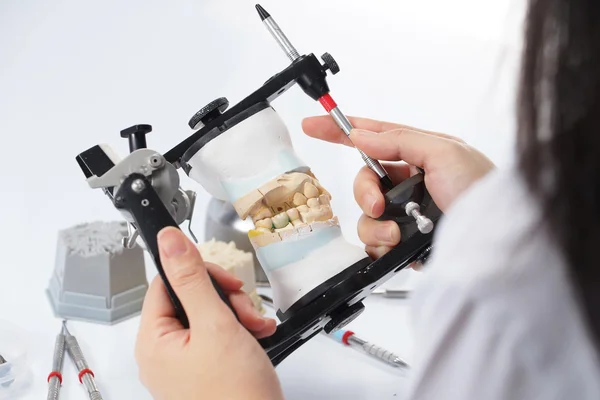 Dental technician working with articulator in dental laboratory