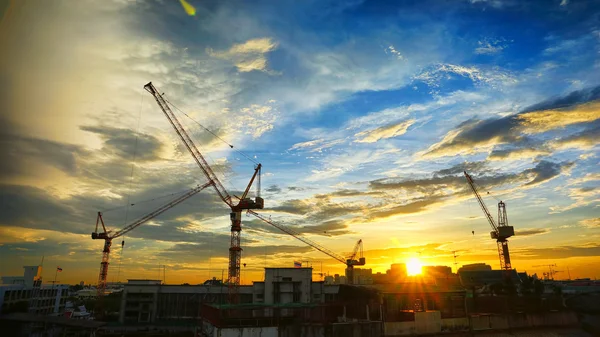 Industrial landscape with silhouettes of cranes on the sunset ba