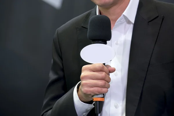 Attractive professional male news reporter holding microphone