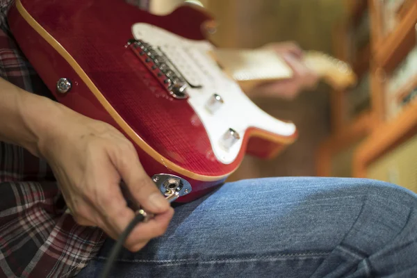 Closed up hand holding jack plug-in to the electric guitar