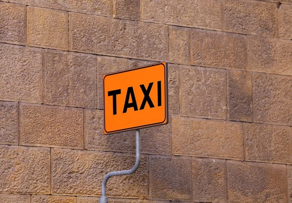 TAXI sign on the taxi stop with a wall as background